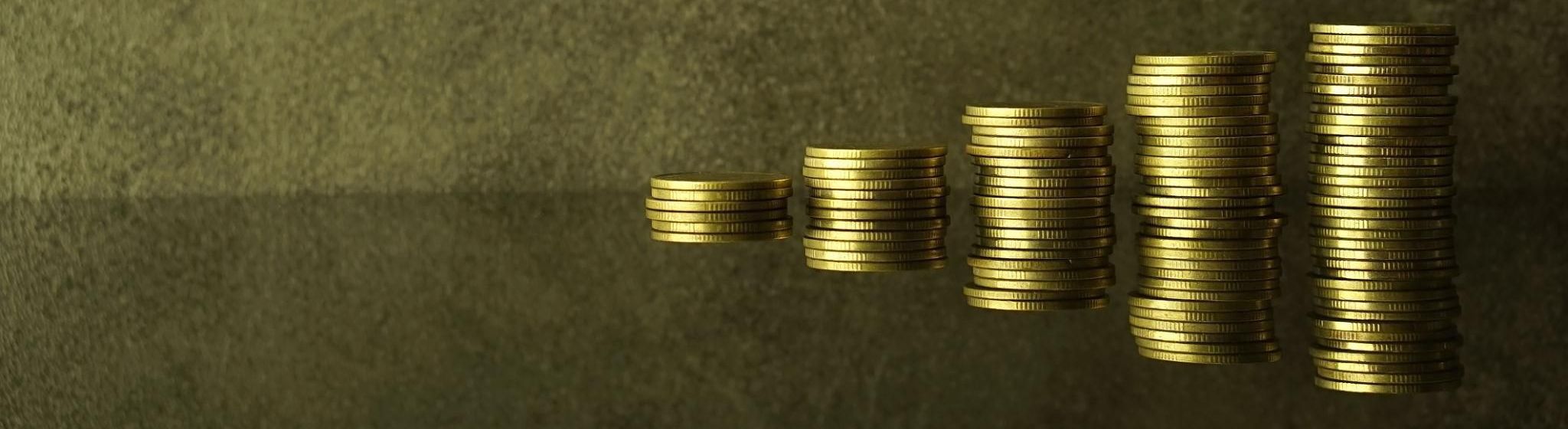 Stacks of gold coins increasing from left to right, symbolizing growing wealth and savings.